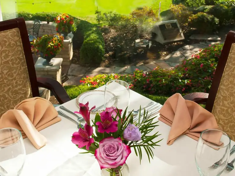 A set table with roses and linen napkins overlooking the course