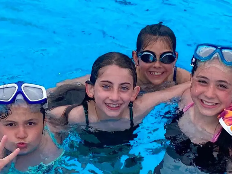 Kids in goggles grin at the camera in the Elgin pool